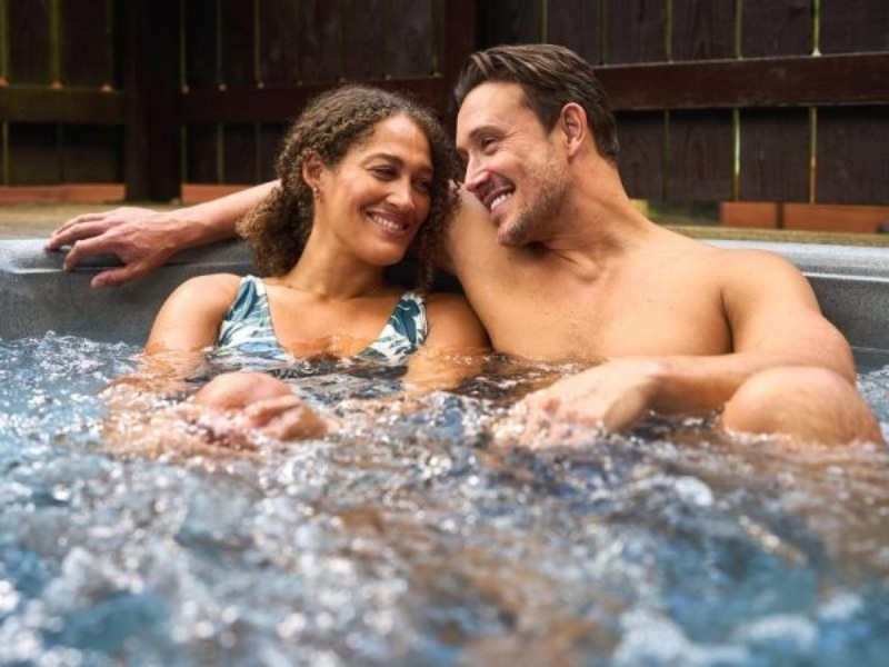 Couple relaxing in a private hot tub at Whitemead Forest Park