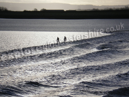 Surfers riding the Severn Bore on a fresh winters morning